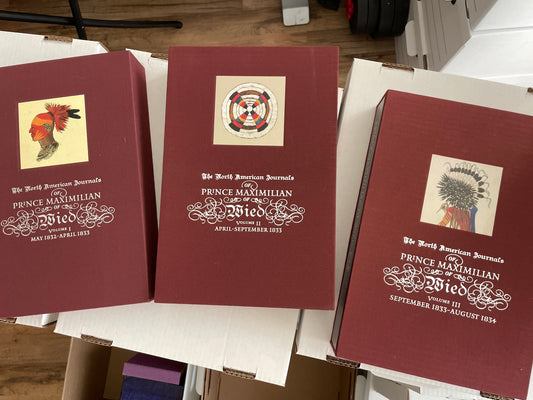 Three burgundy volumes of The North American Journals of Prince Maximilian of Wied, with illustrated panels and decorative white titles.