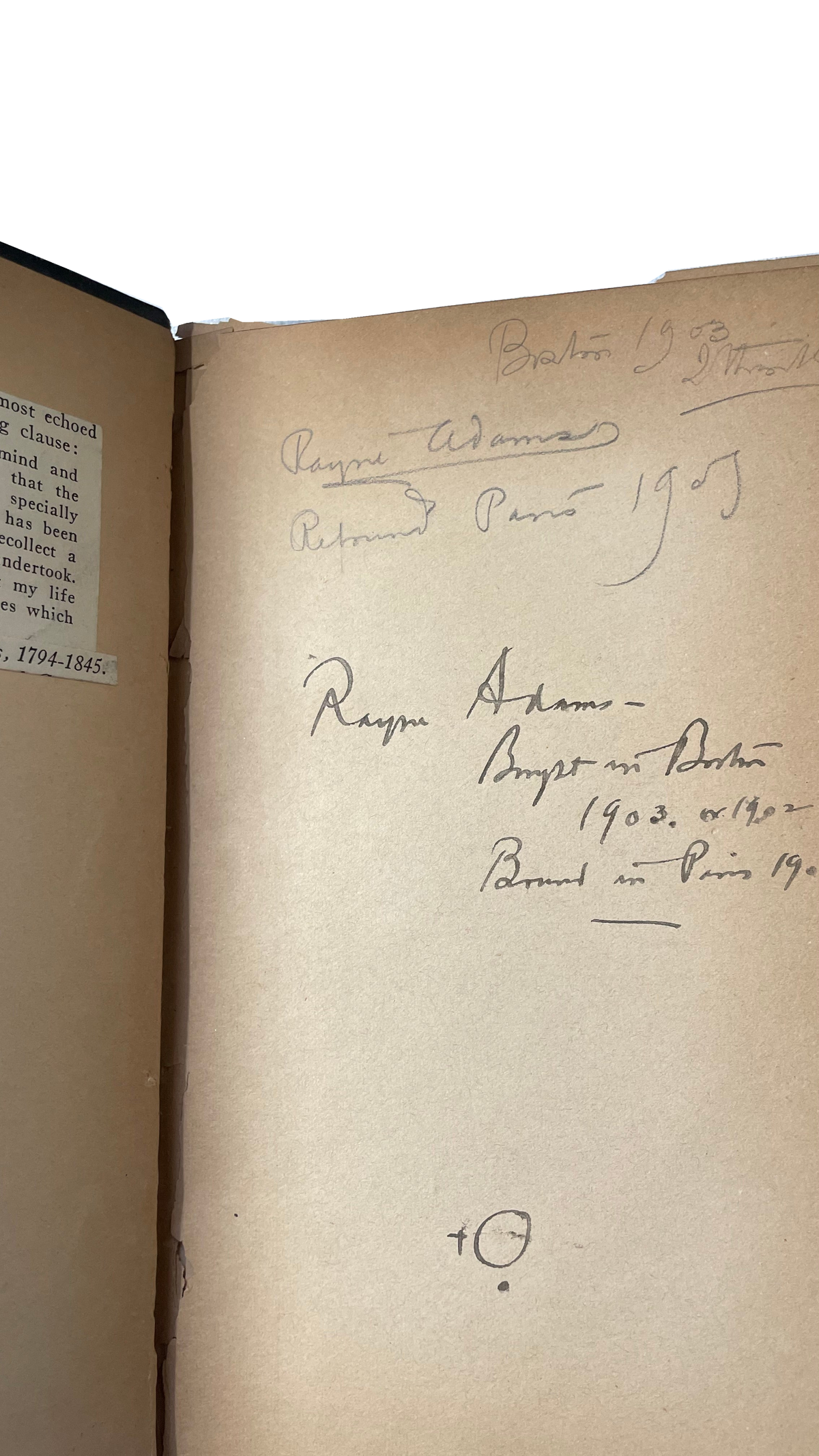 Close view of handwritten ownership and binding notes on a brown endpaper, beside a printed clipping and worn inner hinge.