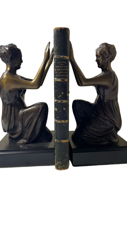 Gilt-lettered green leather spine of Thoughts of the Emperor Marcus Aurelius Antoninus, with visible surface wear, between figurative bookends.