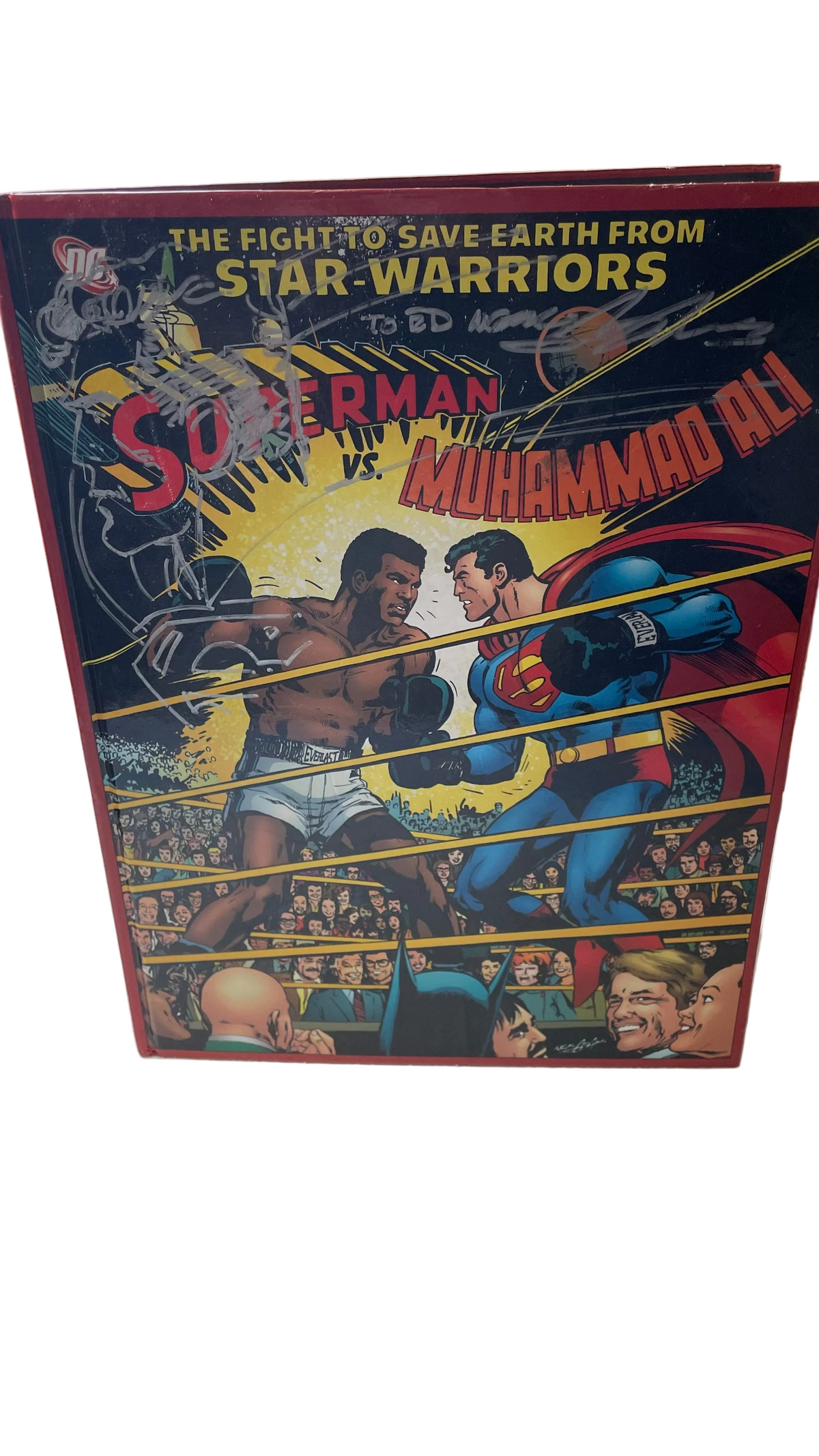 Superman vs. Muhammad Ali standing upright, with a silver-marker drawing and inscription on its cover.