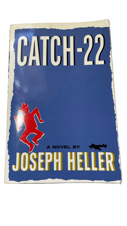 Blue front dust jacket of Catch-22 by Joseph Heller, with a red figure and black airplane silhouette.