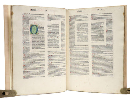 Open pages of Biblia Latina with the Glossa Ordinaria (c. 1480), showing columns of text, red flourishes and a large blue-and-green initial.