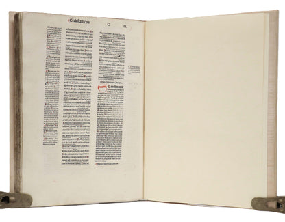 Biblia Latina with the Glossa Ordinaria open to a text-filled left page with a red initial, facing a blank cream page.