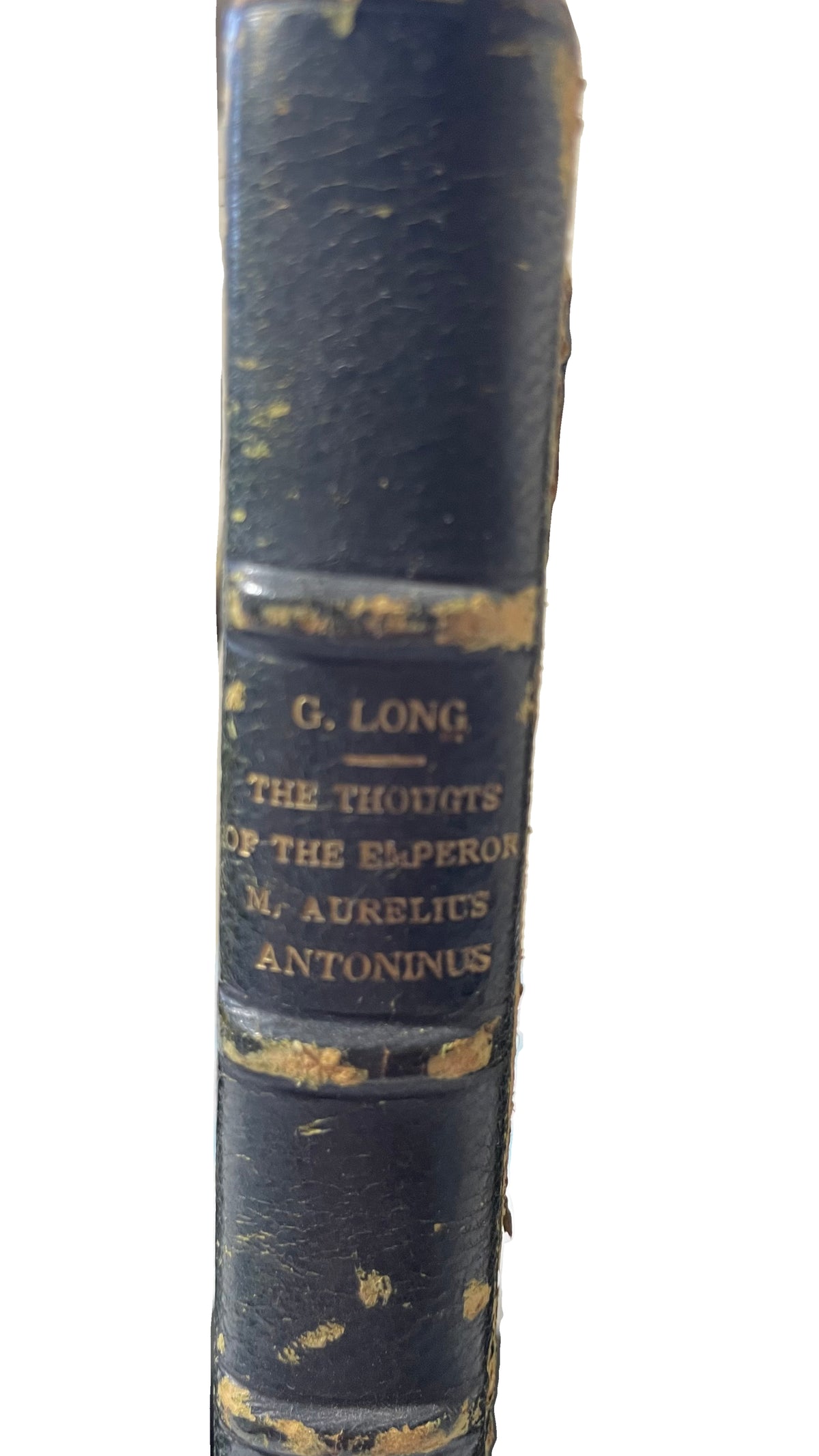 Close-up of the gilt title on the green leather spine of Thoughts of the Emperor Marcus Aurelius Antoninus, with worn bands, peeling leather and projecting fibers visible.
