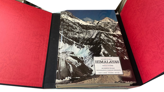 Himalayas with its mountain-photo dust jacket inside an open black case lined in red.