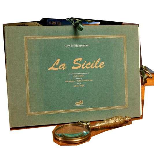 Guy de Maupassant, La Sicile: green cloth portfolio with gold-colored lettering and ribbon ties, standing behind a magnifying glass