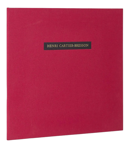 Red cloth portfolio cover with a black label bearing Henri Cartier-Bresson’s name in gold lettering.